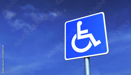 Road sign "Parking for the disabled" on a metal pole, against a blue sky