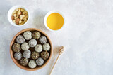 Healthy vegetarian balls with cashews, hazelnuts, peanut butter and almond with honey in the clay bowl on the light background. Vegetarian, organic food. Flat lay with copy space.