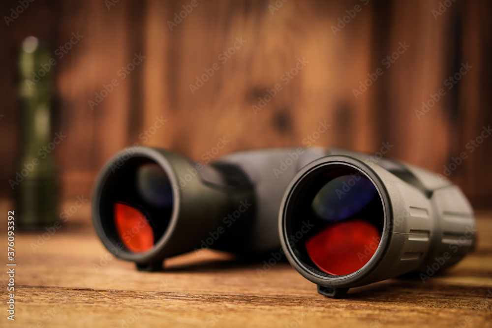 Detail close up of army - hunting binocular and flashlight on a blurred wooden background. Detail close up of army - hunting binocular and flashlight on a blurred wooden background.