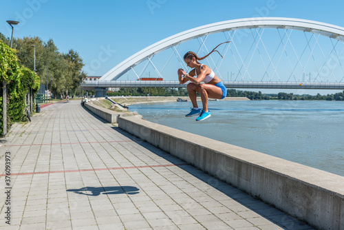 Young sexy strong fit woman in shorts jump with high knees as outdoor hardcore cardio cross workout training © Srdjan