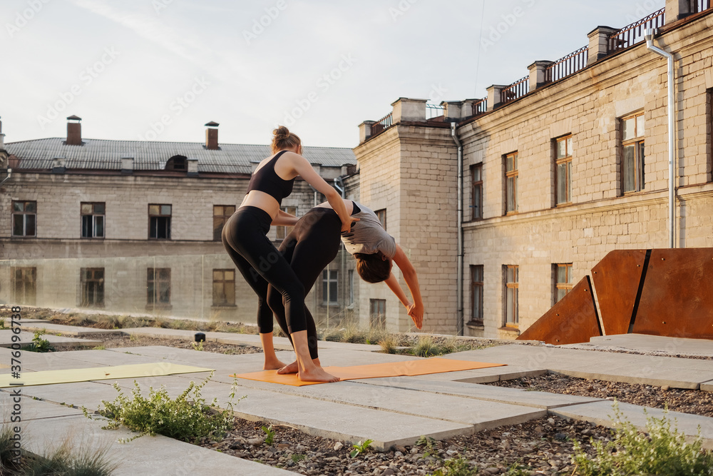 Two young girls practicing stretching and yoga workout exercise together on the terrace