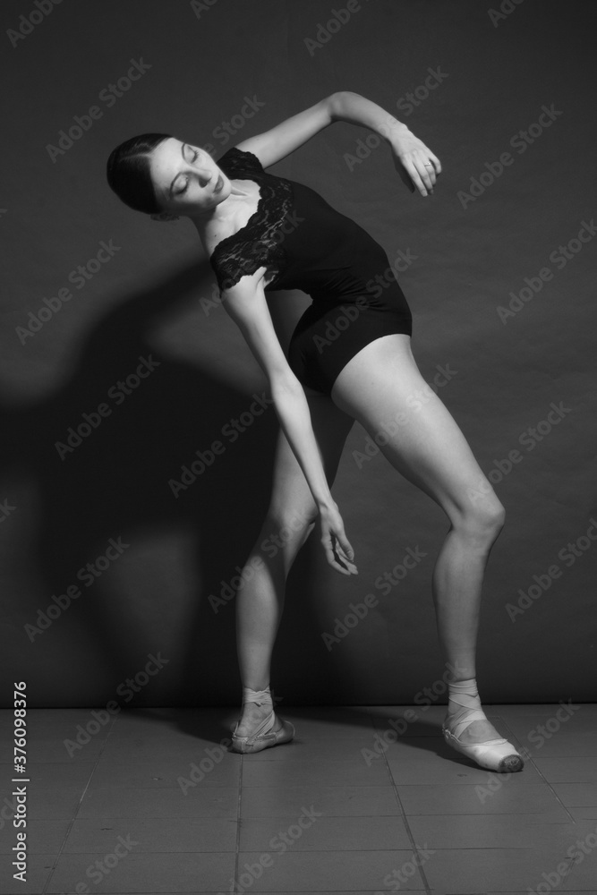 black and white dramatic vintage portrait of a girl, dancing ballerina in a black bodysuit in the Studio on gray background