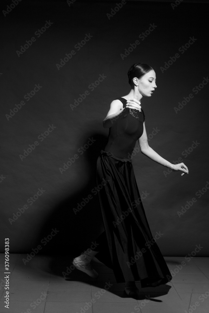 black and white dramatic vintage portrait of a girl, dancing ballerina in a black bodysuit in the Studio on gray background