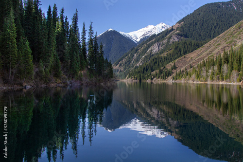 Alpine lake Kolsay in Kazakkhstan. Coniferous forest-covered mountain slopes are reflected in the water. © Тамара Андреева