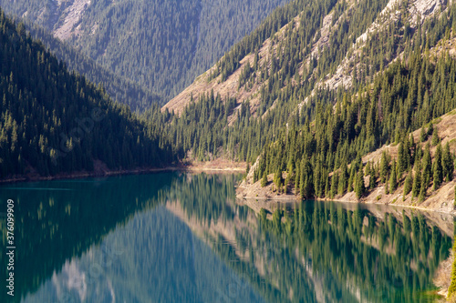 Fototapeta Naklejka Na Ścianę i Meble -  Alpine lake Kolsay in Kazakkhstan. Coniferous forest-covered mountain slopes are reflected in the water.