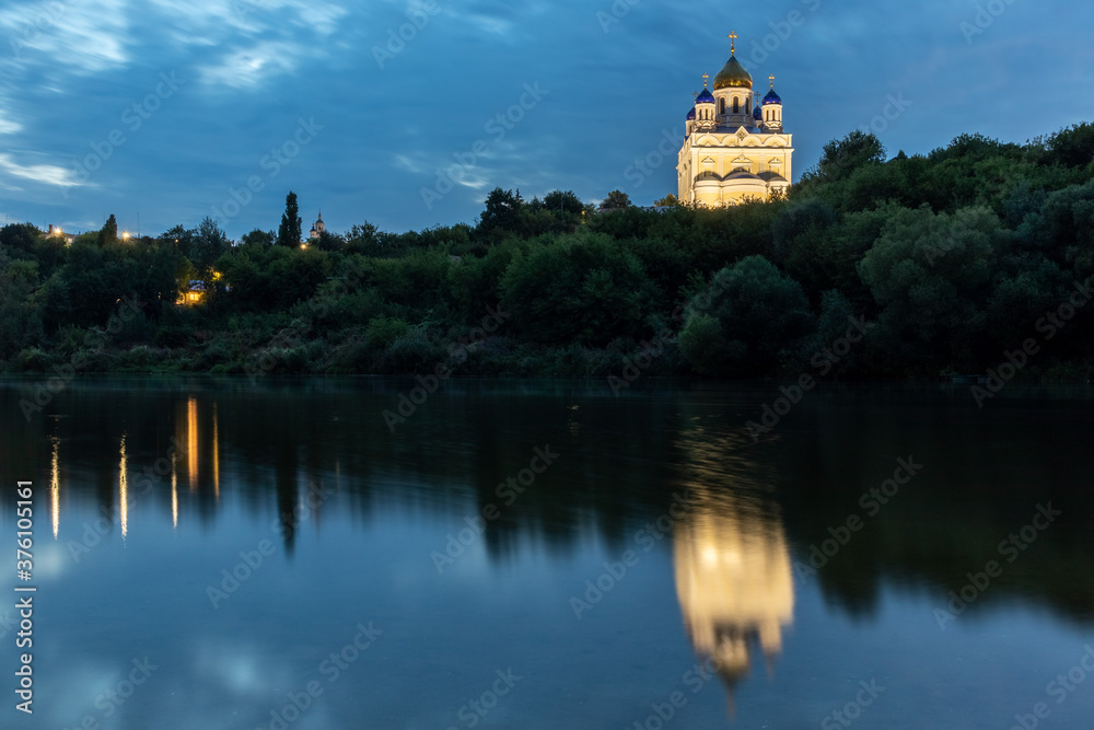 Russia, the city of Yelets, view of the high Bank of the Sosna river and the Cathedral of the ascension of the Lord with the reflection in the water at dusck