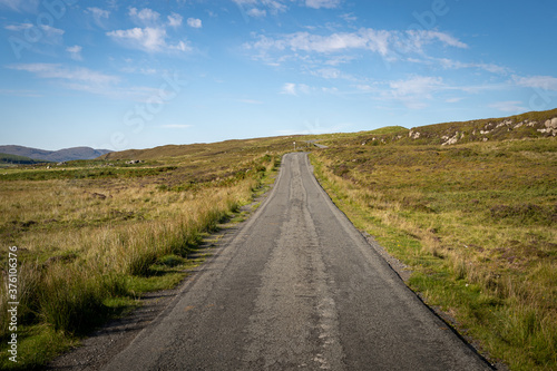 Straight single track road with turns at the end in Scottish Highlands, UK. Beautiful summer sunny day
