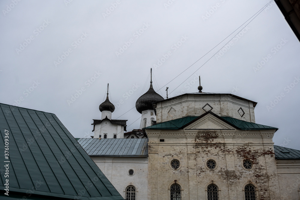 an old stone fortress-monastery with towers and internal buildings against the background of a rainy sky