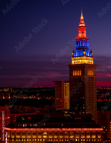 Night view of Cleveland cityscape covered in blue, purple and red shades at night / late sunset with illuminated buildings and suburbs in the background