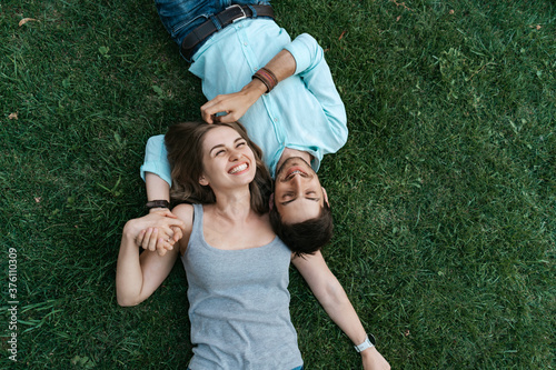 Close up portrait of carefree couple lying on grass together in love