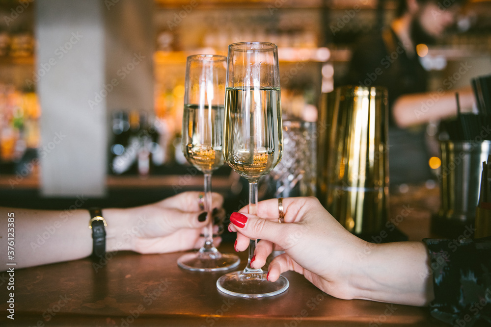 2 women holding prosecco glasses in a bar