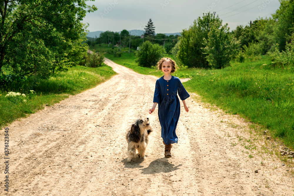 Little girl running with her dog outdoors in rural areas in summer.