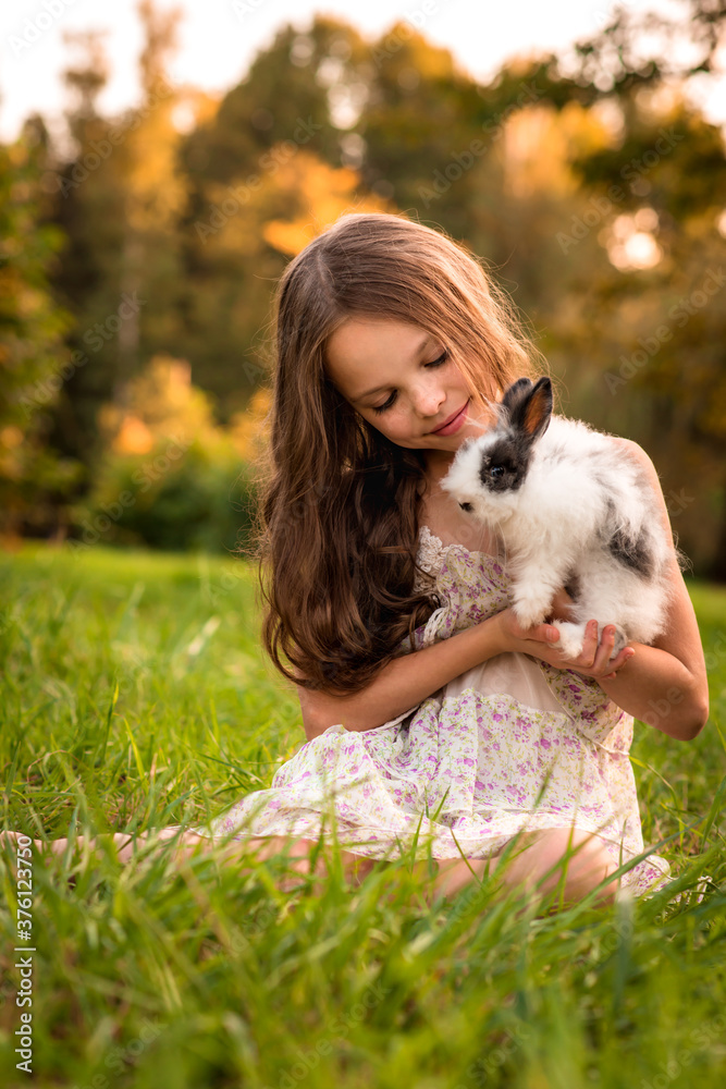Happy little child girl with cute rabbit. Portrait of kid with pet.