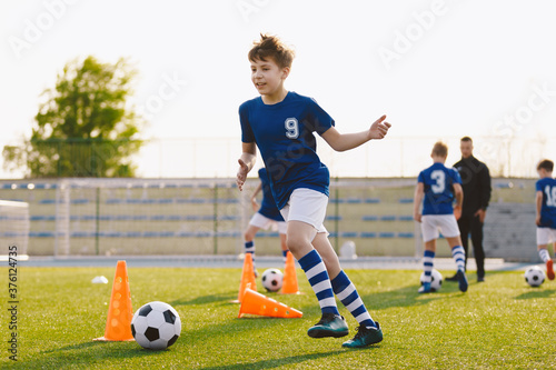 Fototapeta Naklejka Na Ścianę i Meble -  Boys running after ball on soccer training unit. Children having fun on football practice session. School physical education class on summer day