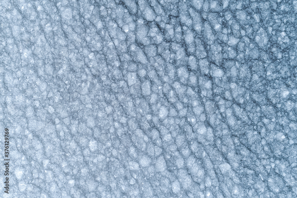 Aerial view of a frozen blue lake. Top down view. Drone image from above. Water surface covered with ice texture. Aerial view of a frozen blue lake. Top down view. Drone image from above. Water surface covered with ice texture.