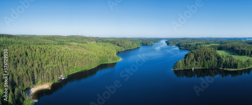 Fototapeta Naklejka Na Ścianę i Meble -  Aerial panorama of beautiful blue lake and green summer forest in Finland. Blue sky. Top view. Sunrise lanscape.