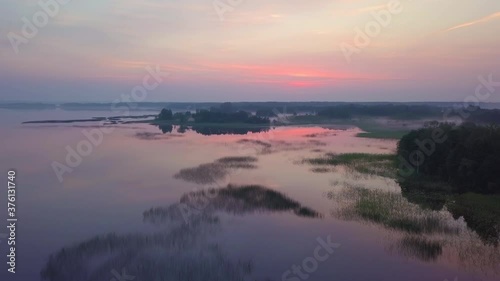 The lake is from above, the drone flies over the silhouettes of the beautiful islands and, illuminated by purple morning sunlight. Aerial flight over the lakes during the fantastic sunrise. 4K