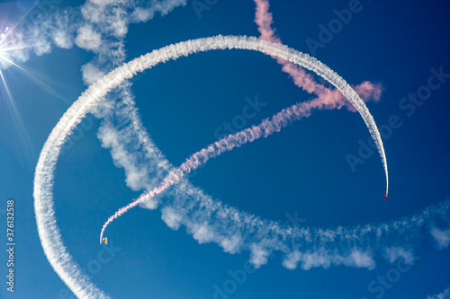 Parachuter and airplane creating white and pink trails of smoke photo