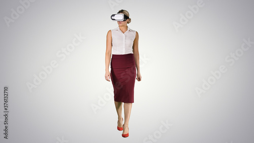 Walking young woman using vr glasses on gradient background.