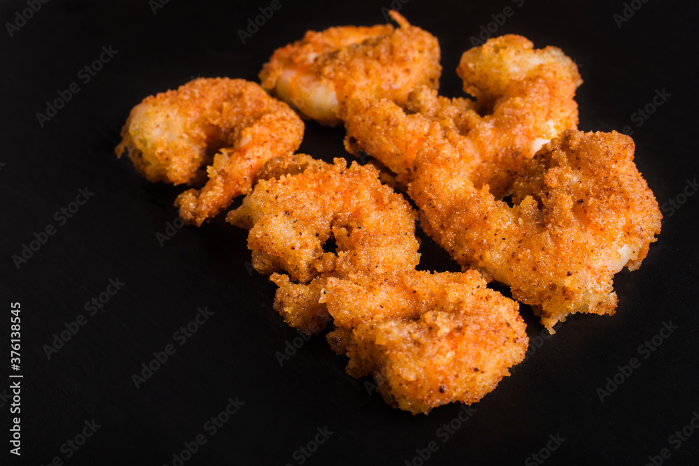 Shrimps in batter on black stone background