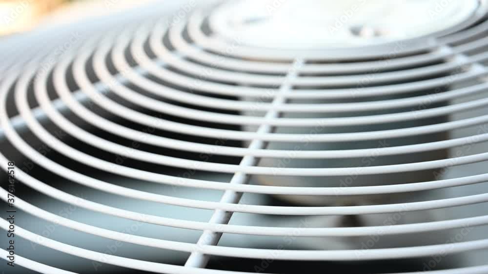 Residential air conditioner with motor fan blade rotating.  AC located outside - sound of wind from AC unit. 