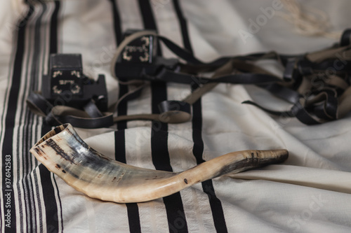 A shofar is placed on a tallit  next to tefillin  jewish religious objects for the holidays 