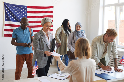 Photography Multi-ethnic group of people registering at polling station decorated with Ameri