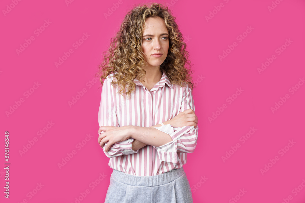 A side shot of a beautiful upset woman with curly hair holding her arms folded. A side shot of a beautiful upset woman with curly hair holding her arms folded.