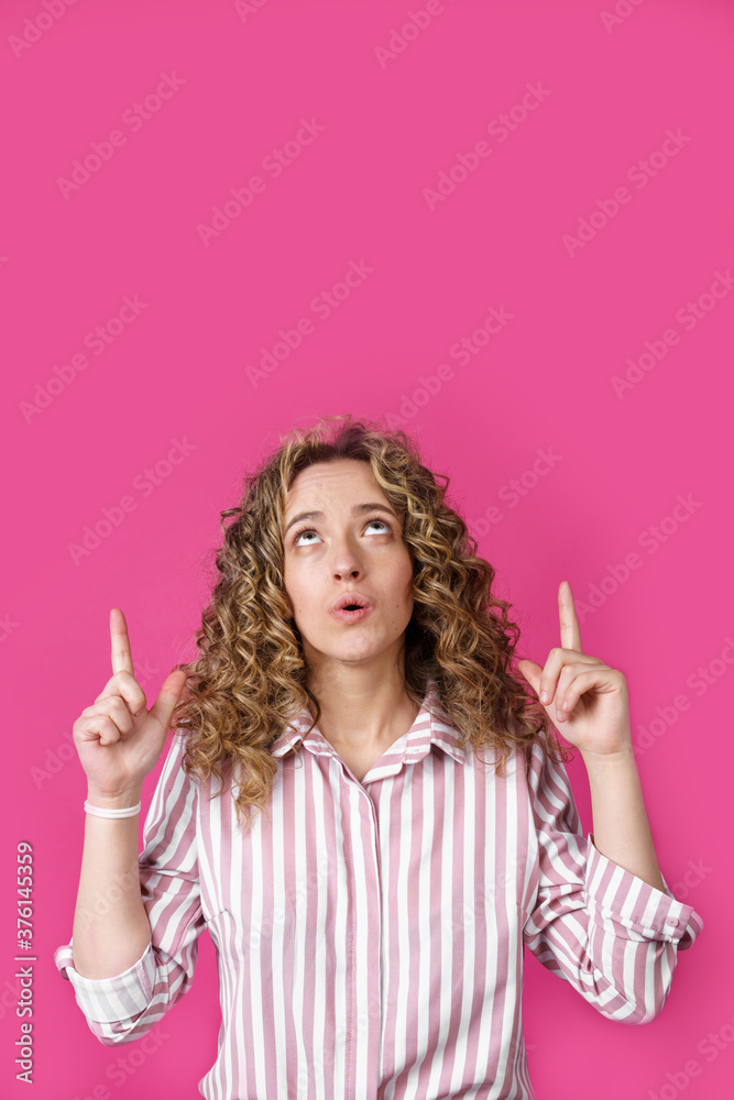 Young beautiful woman, amazed and surprised, looking up and pointing with fingers and raised hands. Young beautiful woman, amazed and surprised, looking up and pointing with fingers and raised hands.