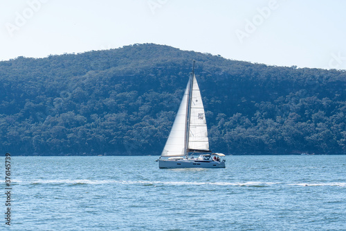 Yacht going by with white sails up in the ocean/ sea on a beautiful spring day.