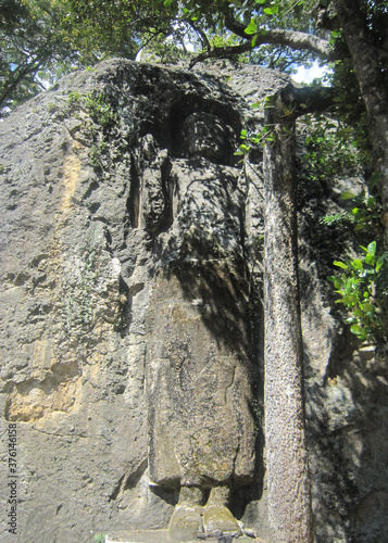 Buddha carved on mountain rock cliff “ The large unfinished Buddha image at Dhowa Raja Maha Vihara or The Dhowa rock temple in Badulla District , Uva Province, Sri Lanka photo