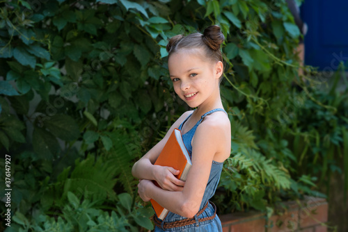 Happy cute child girl holding books.