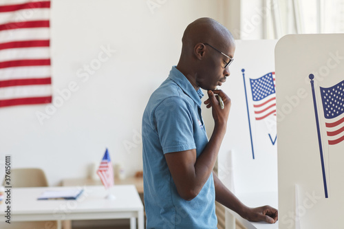 Fotografía Side view portrait of young African-American man standing in voting booth and th