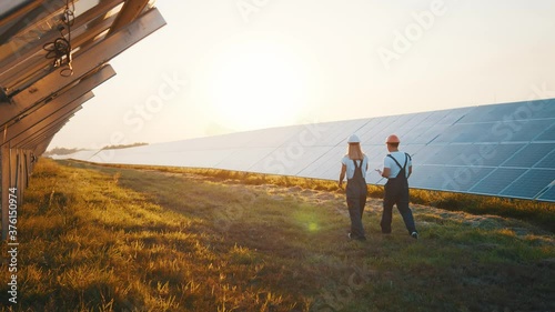 Solar park. Ecological field. Rows of huge photovoltaic solar power panels installed on rural field. Renewable energy. Clean electricity. Workers.