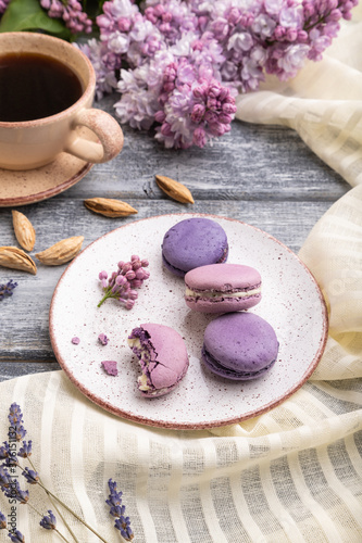 Purple macarons or macaroons cakes with cup of coffee on a gray wooden background. Side view.