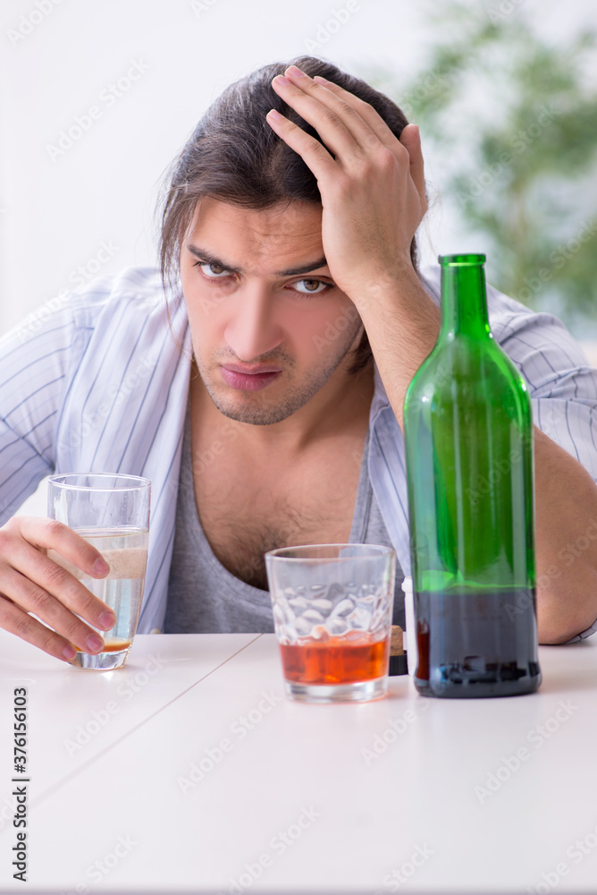 Young male alcoholic drinking whiskey at home Young male alcoholic drinking whiskey at home