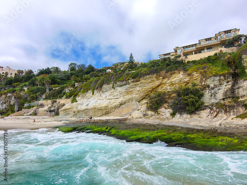 stunning aerial shot of the green ocean water, crashing waves, blue skies and the beach at 1000 Steps Beach in Laguna Beach California USA photo