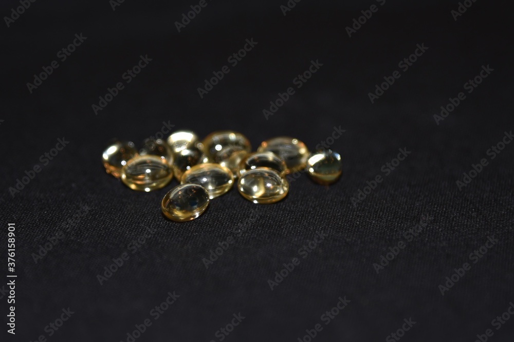 Vitamin D gel capsules against a black background with selected focus Vitamin D gel capsules against a black background with selected focus