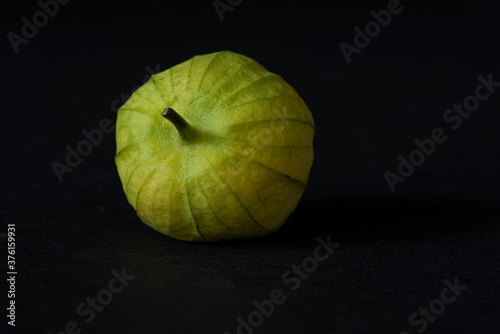 Unwashed green tomatillo on black background, viewed from dinner angle- California produce concept