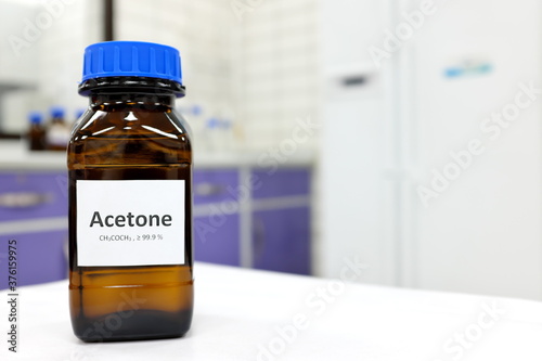 Selective focus of pure acetone solution in brown glass amber bottle inside a chemistry laboratory. White background with copy space. photo
