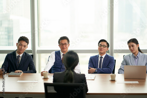 female asian candidate being interviewed by a group of business people