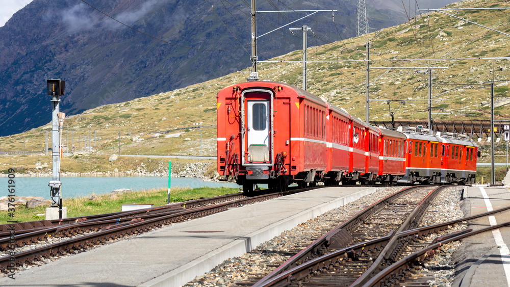 Bernina pass, Switzerland. The famous red train is leaving the Ospizio Bernina station to Saint Moritz. Best of Swiss. Famous destination and tourists attraction Bernina pass, Switzerland. The famous red train is leaving the Ospizio Bernina station to Saint Moritz. Best of Swiss. Famous destination and tourists attraction