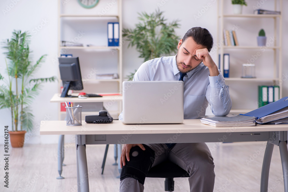 Young leg injured employee working in the office