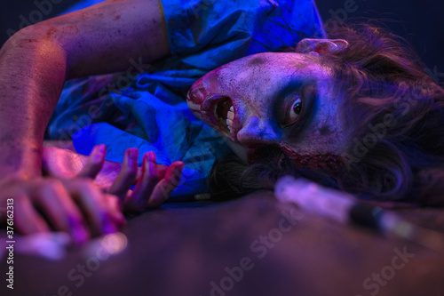 Halloween zombie with coronavirus Woman wearing face mask protective for Covid-19 reaching for the antidote on the floor. Horror infection concept photo