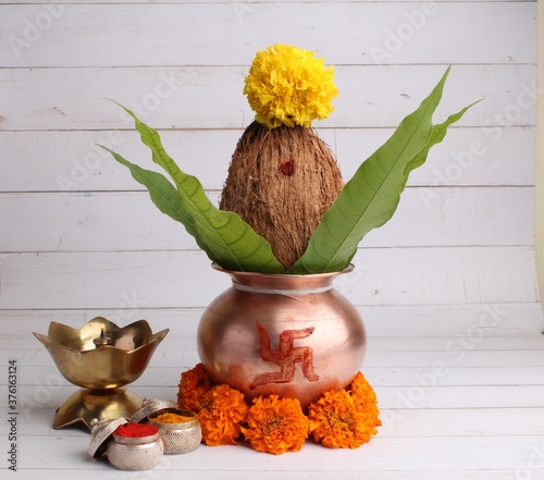 copper kalash with coconut and mango leaf with haldi kumkum, diya and floral decoration. essential in hindu puja.