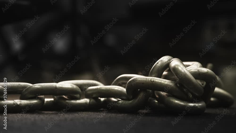 Heavy metal chains on floor of gym weight room, Medium Shot, Pan Right, Slow Motion Heavy metal chains on floor of gym weight room, Medium Shot, Pan Right, Slow Motion