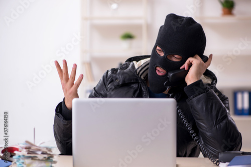 Young male burglar in the office photo