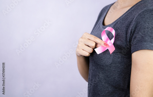 Women hold a pink ribbon and attach it to their breasts to tell or acknowledge breast cancer. Concept of health care and medicine.