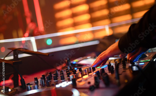 A male DJ is mixing songs on his players on stage as fun, youth, entertainment and stage festivals.