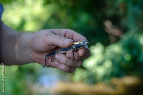 A man's hand holds a plastic wobbler with three hooks. photo